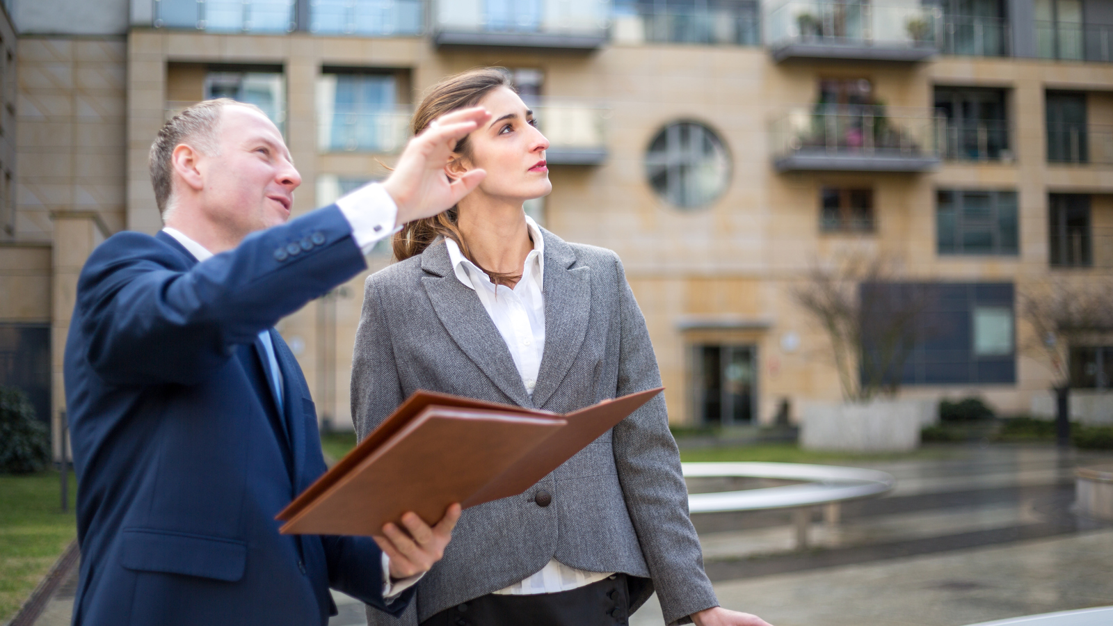 A man holding a clipboard and pointing with a woman 