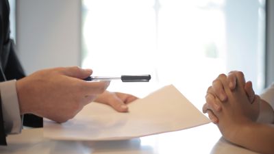 A property manager's hands handing documents to a second pair of hands