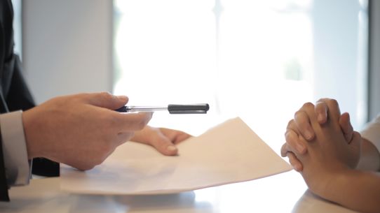 A property manager's hands handing documents to a second pair of hands