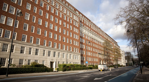 A wide shot of a brown apartment complex from the other side of the street