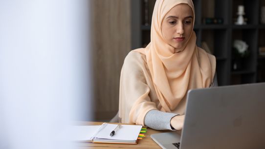 A woman sitting at a desk with a laptop